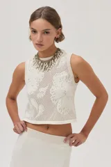 Top tejido de punto calado color crudo con diseño de flores, escote redondo y lurex en el escote.