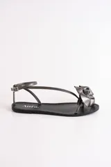 Sandalias bajas de cuero color suela, con tiras finas y aplique de flor roja en el empeine.