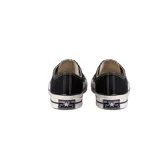 Zapatillas Converse Chuck 70 Ox de lona negra con detalles en blanco, cordones blancos y suela de goma blanca con doble línea negra.