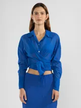 Camisa negra de manga larga con lazo en la cintura y botones nacarados. Confeccionada en 100% algodón y detalle de Polonio en cobre.