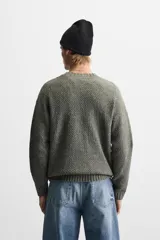 Sweater verde oliva de punto con cuello redondo y diseño de trenzas en el centro.