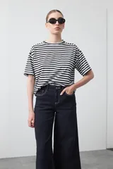 Pantalón de denim azul oscuro con corte flare, ajustado en la cadera y amplio en el ruedo. Presenta pespuntes a contratono en color blanco que resaltan las costuras.