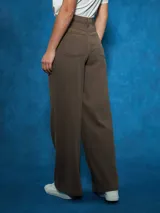 Pantalón de jean negro de tiro alto con corte ancho y pierna recta. Presenta costuras visibles y bolsillos tipo cinco bolsillos.