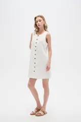 Vestido blanco de lino, corte entallado, con botones frontales, cuello a la base y breteles anchos.