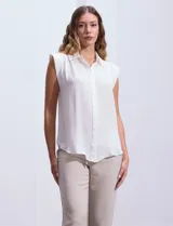 Blusa negra de gasa marca Tahari, con cuello a la base con solapa, abertura central con botones ocultos y detalle plisado en hombros.