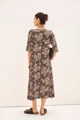 Vestido midi con estampado floral en tonos marrones, naranjas y blancos. Tiene mangas 3/4, escote en V y corte en línea A.