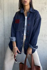 Sobrecamisa de jean azul con botones color rojo y diseño clásico, de corte relajado.