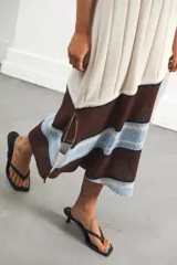 Vestido midi tejido en punto canalé negro con detalles en lurex plateado. Presenta calado artesanal en el ruedo, abertura lateral y etiqueta de cuero en la parte trasera del cuello.