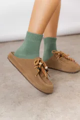 Zueco de cuero gamuzado color beige, con cordones decorativos con cuentas y piezas envueltas en cuero. Tiene plantilla acolchada y base liviana.