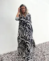 Vestido camisero largo con estampado abstracto en blanco y negro, cierre frontal con botones, mangas 3/4 y cuello camisero.