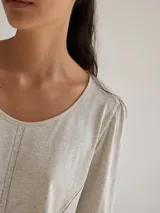 Remera blanca de algodón con escote redondo, mangas largas y pespuntes verticales a contratono.