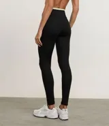 Conjunto deportivo de dos piezas, compuesto por un top deportivo de tirantes finos y un pantalón legging ajustado. Ambas prendas son de color gris oscuro, con el detalle de una banda elástica de color rosado en la cintura del legging.