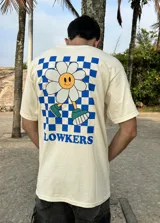 Remera beige de algodón con estampa en la espalda de una flor sonriente sobre un fondo a cuadros azules y texto "FLOWKERS".