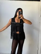 Chaleco negro de símil gamuza con flecos y tachas plateadas.