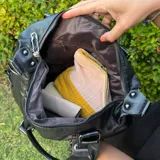 Bolso tipo tote de eco cuero negro con doble asa de hombro y cierre superior.