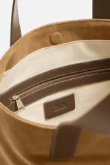 Bolso tipo shopper color marrón claro, fabricado en cuero con acabado serraje. Tiene doble asa de mano de cuero y un bolsillo interior con cierre.