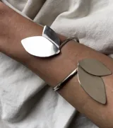 Brazalete abierto de metal dorado con apliques de hojas.
