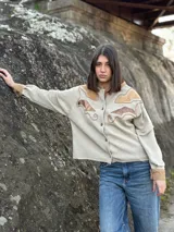 Campera color beige con apliques de cuero marrón en hombros y frente, corte recto y cierre con botones.