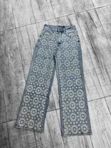 Pantalón de jean celeste con bordado de flores blancas. Corte recto y tiro alto.