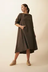 Vestido largo debajo de la rodilla, acampanado, color marrón, con cuello bote, bolsillos laterales y mangas 3/4 con detalle de tajo.