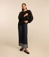 Blusa negra de crepé con cuello redondo, mangas largas abullonadas con puños elásticos y textura plisada.