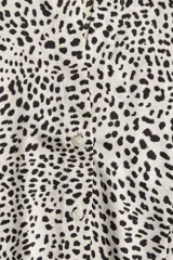 Camisa entallada de manga larga en tejido elástico de satén con estampado de leopardo. Modelo con cuello abierto, botonadura frontal y puños abotonados con abertura. Pinzas adelante y atrás para estilizar la figura.