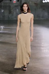Vestido midi de encaje color beige, sin mangas, con espalda descubierta y bajo asimétrico con volados.