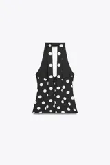 Top negro con estampado de lunares blancos, cuello halter, escote en pico y lazo en la espalda.