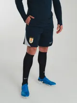 Short de entrenamiento Nike azul marino con logo blanco y escudo de la selección uruguaya.