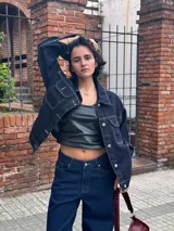 Campera de jean azul oscuro con costuras en hilo ocre, corte recto, cuello clásico, bolsillos frontales con solapa y cierre con botones metálicos.