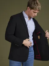Blazer azul marino de corte clásico con solapa de muesca, cierre de dos botones y bolsillos laterales con solapa.