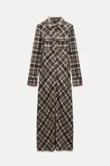 Vestido largo tipo camisero con estampado de cuadros en tonos marrón, negro y blanco. Tiene cuello solapa, mangas largas con puños abotonados, dos bolsillos de parche con solapa en el pecho y cierre frontal con botones a presión.