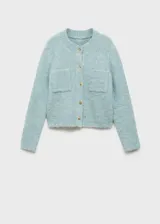 Chaqueta color celeste de tejido bouclé con cuello redondo, cierre frontal con botones efecto joya, dos bolsillos de parche frontales y mangas largas.