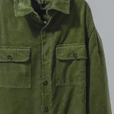 Campera negra de pana con cuello camisero, cierre frontal con botones a presión, dos bolsillos de parche en el pecho y corte recto.