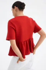 Top rojo de manga corta con escote redondo, botones forrados adelante y peplum.