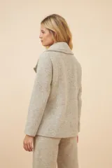 Chaquetón color crema con doble solapa, abrochadura doble, bolsillos delanteros y forro al tono.