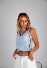 Blusa celeste de crochet con cuello redondo y ribete marrón.