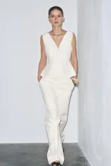 Pantalón de tiro medio confeccionado en hilatura de algodón color blanco. Cuenta con trabillas en la cintura, bolsillos laterales ocultos en costura y cierre frontal con cremallera, botón y ganchos metálicos.