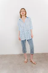 Camisa celeste de algodón con bordado calado tipo broderie, manga larga con puño angosto y botones al frente.