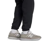 Pantalón de jogging negro de felpa francesa con cintura y tobillos elastizados, cordón de ajuste externo, bolsillos laterales y trasero. Logo bordado de New Balance en el muslo izquierdo.