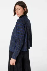 Sweater crop color crudo con rayas verticales negras y diseño de trenzas.