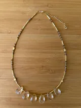 Collar corto dorado con cuentas de cristal facetado color marrón y colgantes de cristal transparente en forma de lágrima.