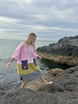 Poncho de toalla de manga corta con bloques de color rosa, verde oliva y gris. Tiene dos bolsillos frontales con estampado floral.