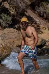 Short de baño blanco con estampado de hojas de palmera verdes, peces amarillos y rayas rojas. Tiene elástico en la cintura, tres bolsillos y logo de la marca en la pierna izquierda.