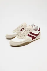 Zapatillas deportivas con combinación de colores blanco, beige y bordó. Suela en contraste color caramelo. Cierre mediante cordones.