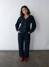 Camisa entallada de denim azul oscuro con cuello en V y cierre frontal con botones. Confeccionada en algodón reciclado con espalda ajustable.