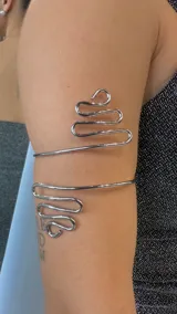 Brazalete plateado para el brazo, con diseño ondulado en los extremos.