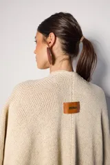 Ruana color beige de tejido de punto con flecos en el ruedo.