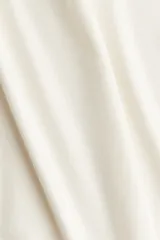 Remera corta de punto fino color blanco, de ajuste entallado con cuello redondo, mangas cortas y terminaciones acanaladas.