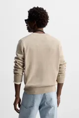 Jersey de punto color beige, con cuello en V y mangas largas.